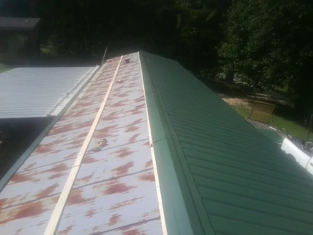 Old rusted panels beside newly installed green metal roofing — Wind Damage Roof Repair by Roofing Brothers in Redmond