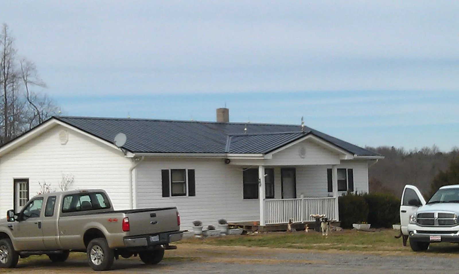 Finished dark metal roof on a white ranch home with work trucks parked in Redmond